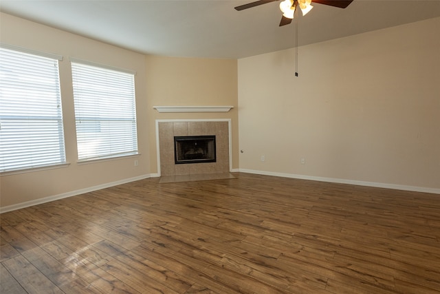 unfurnished living room with ceiling fan, a fireplace, and dark wood-type flooring