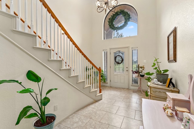 entryway featuring light tile patterned flooring, a notable chandelier, and a high ceiling