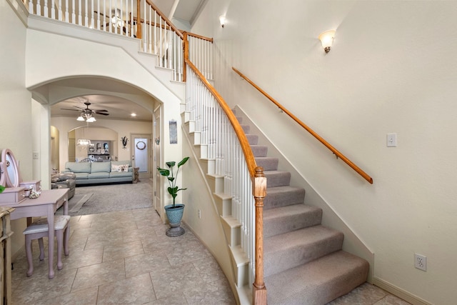 stairs featuring a towering ceiling, tile patterned flooring, and ceiling fan