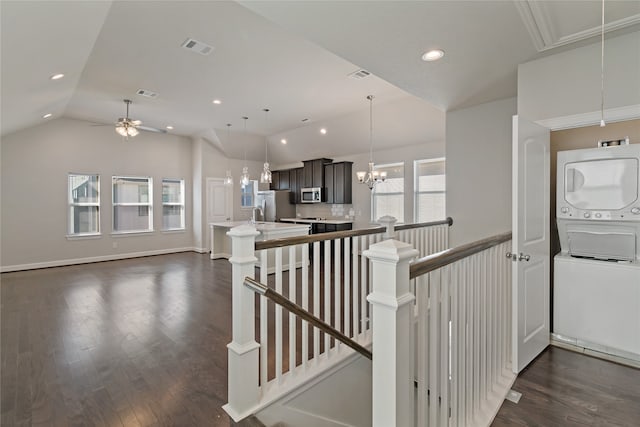 stairway featuring hardwood / wood-style floors, ceiling fan, stacked washer / dryer, and vaulted ceiling