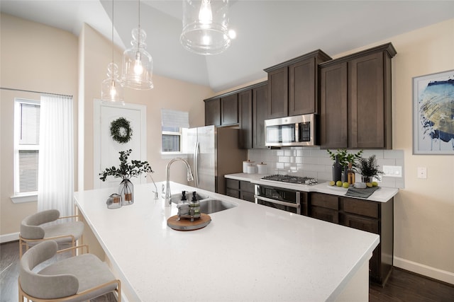 kitchen with hanging light fixtures, sink, an island with sink, dark hardwood / wood-style floors, and appliances with stainless steel finishes