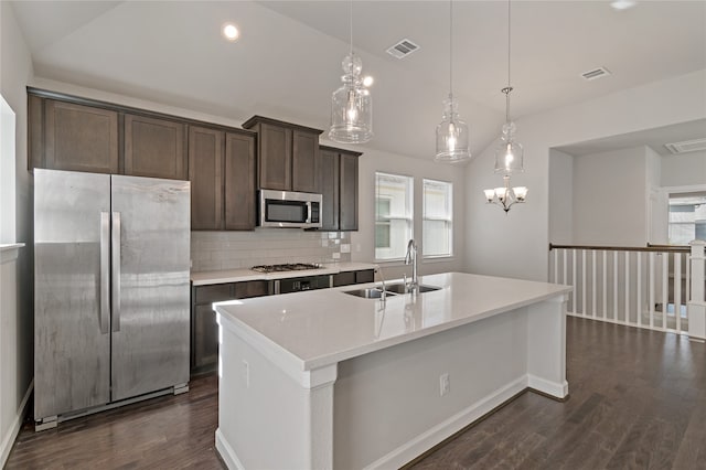 kitchen with sink, appliances with stainless steel finishes, hanging light fixtures, a kitchen island with sink, and dark wood-type flooring