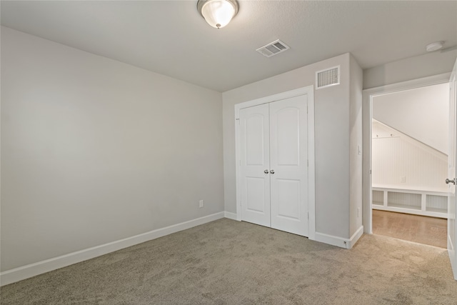 unfurnished bedroom featuring light carpet and a closet