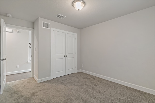 unfurnished bedroom featuring a closet and light colored carpet