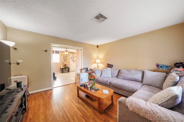 living room featuring a textured ceiling, hardwood / wood-style flooring, and ceiling fan