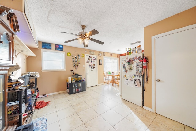 kitchen with a textured ceiling, plenty of natural light, light tile patterned floors, and white refrigerator