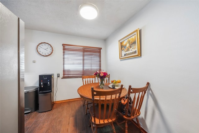 dining room featuring dark wood-type flooring and a textured ceiling