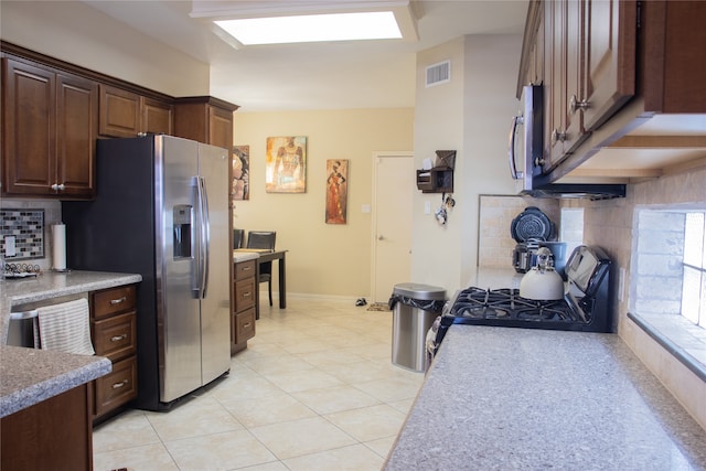 kitchen with backsplash, dark brown cabinetry, light tile patterned flooring, and stainless steel appliances