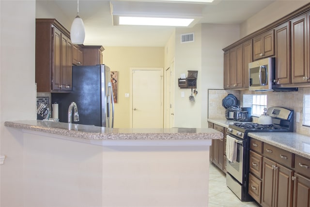 kitchen featuring tasteful backsplash, stainless steel appliances, light tile patterned floors, sink, and kitchen peninsula