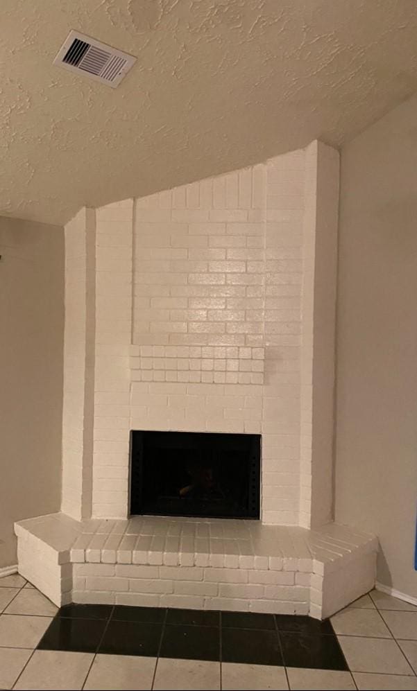 interior details featuring a textured ceiling and a brick fireplace