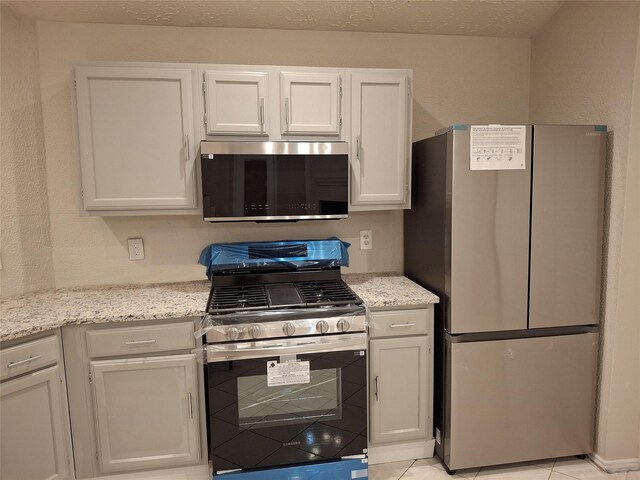 16703 Sentinel Dr, Houston, TX 77053 - kitchen featuring stainless steel appliances, white cabinetry, light stone countertops, and light tile patterned flooring