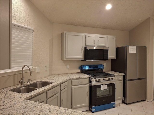 16703 Sentinel Dr, Houston, TX 77053 - kitchen featuring appliances with stainless steel finishes, light tile patterned floors, light stone countertops, white cabinets, and a textured ceiling