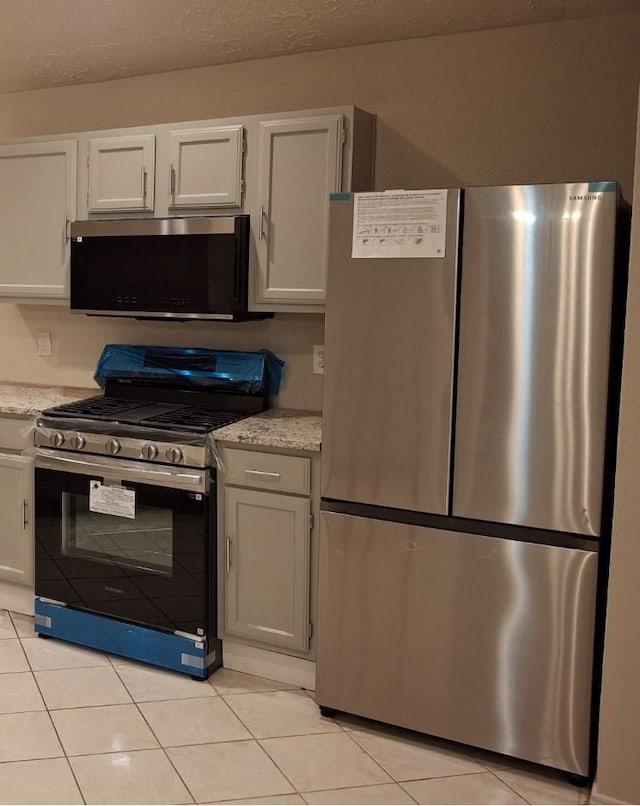 16703 Sentinel Dr, Houston, TX 77053 - kitchen with appliances with stainless steel finishes, light tile patterned floors, and white cabinets