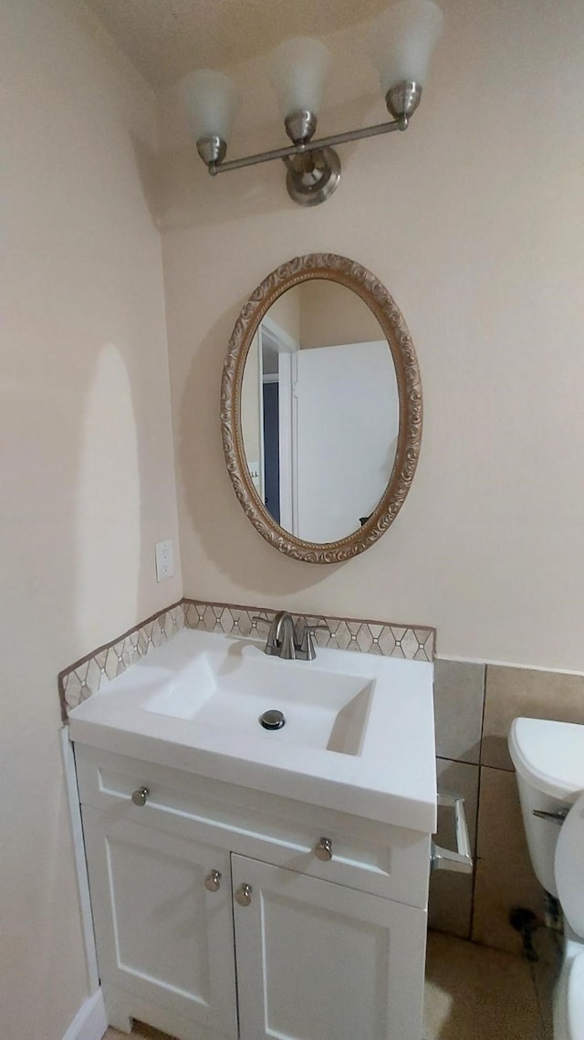 bathroom with vanity, toilet, and tile walls