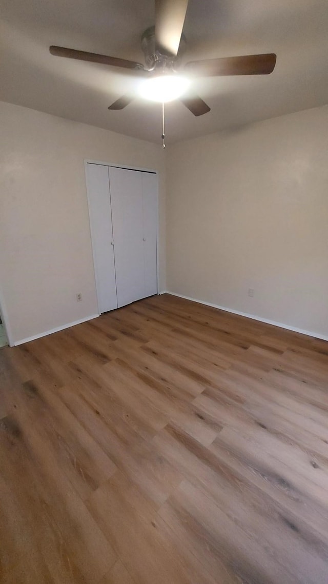 unfurnished bedroom featuring ceiling fan, light wood-type flooring, and a closet