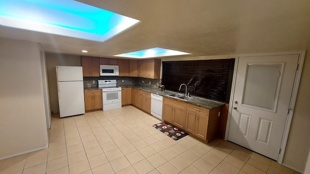 kitchen featuring white appliances, backsplash, sink, a skylight, and light tile patterned floors