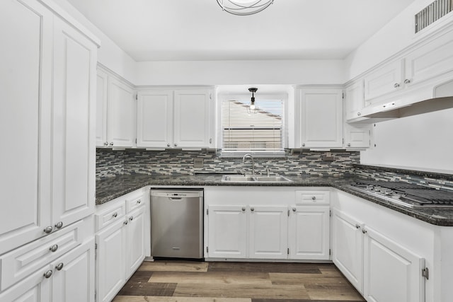 kitchen with stainless steel appliances, dark hardwood / wood-style flooring, white cabinets, sink, and dark stone countertops