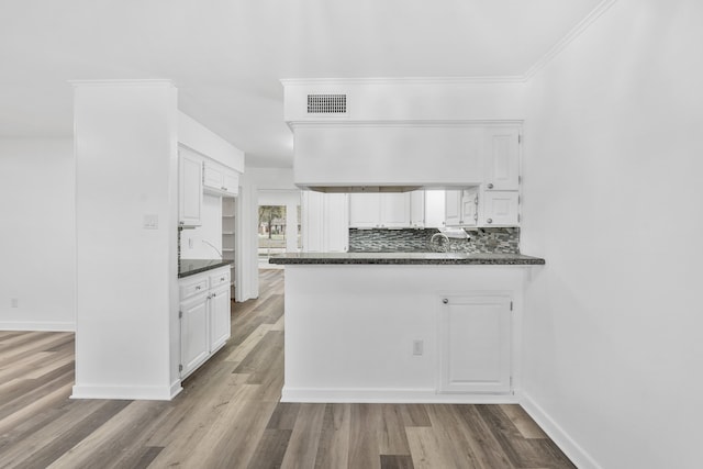 kitchen featuring backsplash, white cabinetry, light hardwood / wood-style flooring, and kitchen peninsula