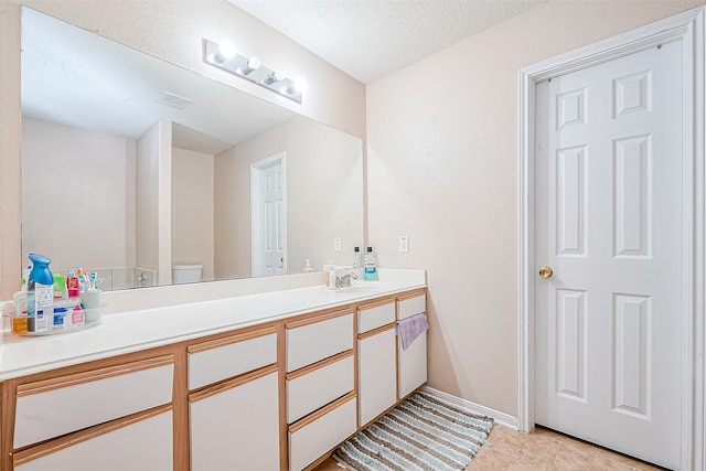 bathroom with tile patterned flooring, vanity, toilet, and a textured ceiling