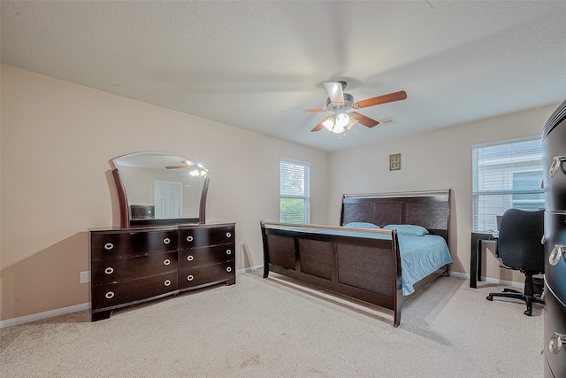 bedroom with a textured ceiling, light carpet, and ceiling fan