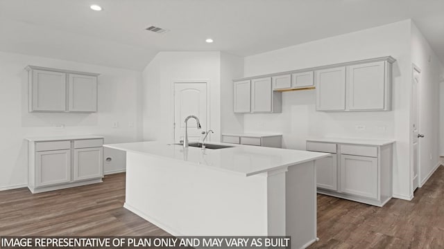 kitchen with gray cabinetry, sink, an island with sink, and dark wood-type flooring