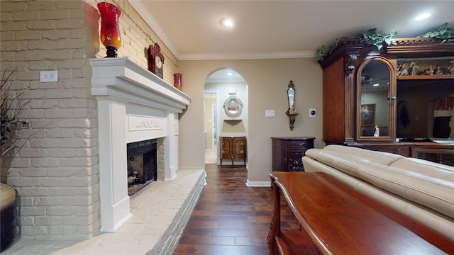 interior space with ornamental molding, a brick fireplace, and dark hardwood / wood-style flooring