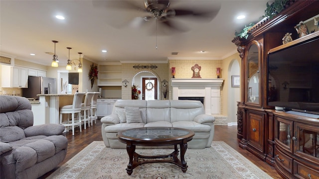 living room with ornamental molding, ceiling fan, and dark hardwood / wood-style floors