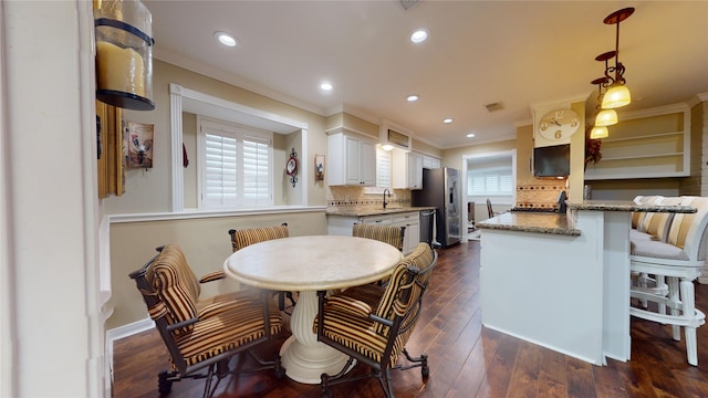 dining area featuring dark wood-type flooring and crown molding