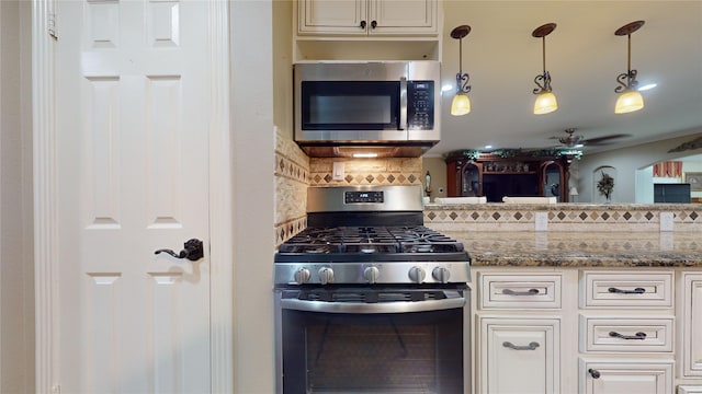 kitchen with light stone counters, appliances with stainless steel finishes, backsplash, hanging light fixtures, and white cabinets