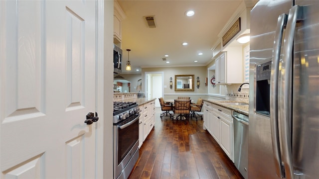 kitchen with dark hardwood / wood-style flooring, white cabinetry, hanging light fixtures, and stainless steel appliances