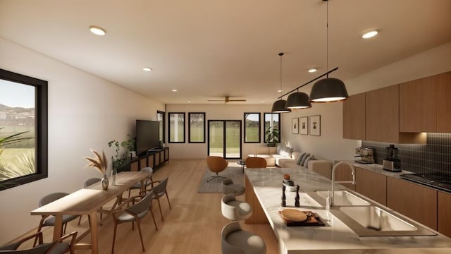 kitchen featuring light wood-type flooring, stovetop, a healthy amount of sunlight, and decorative light fixtures