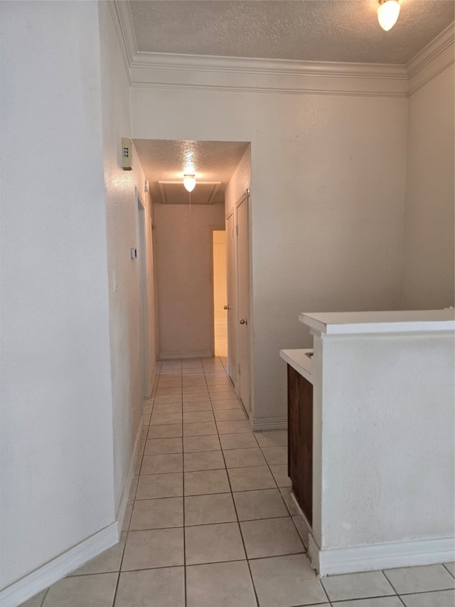 hall featuring a textured ceiling, light tile patterned floors, and ornamental molding