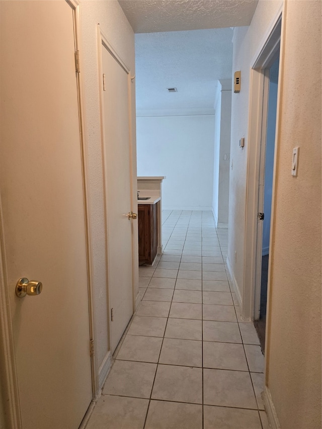 hall featuring a textured ceiling and light tile patterned flooring