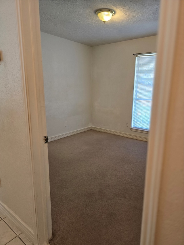 empty room featuring a textured ceiling and light carpet