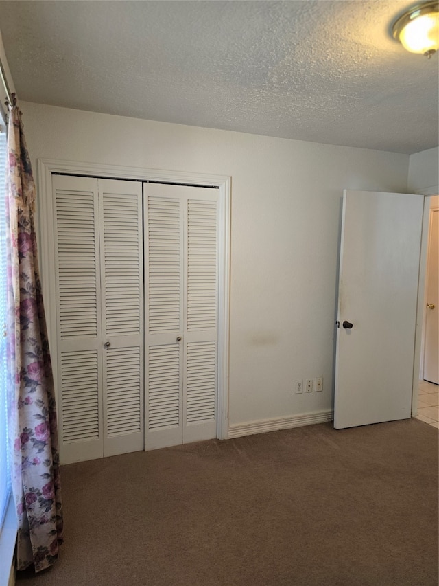 unfurnished bedroom with a closet, a textured ceiling, and carpet flooring