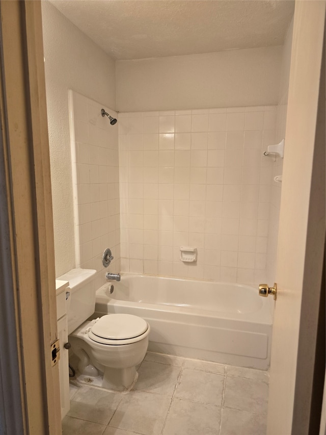 bathroom featuring toilet, tiled shower / bath, a textured ceiling, and tile patterned flooring