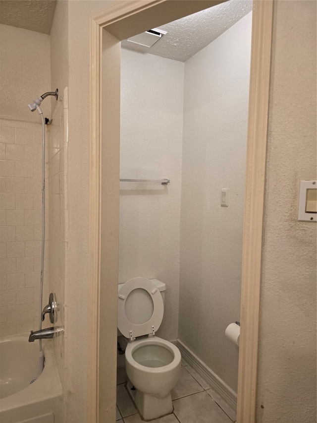 bathroom featuring toilet, tiled shower / bath, a textured ceiling, and tile patterned flooring