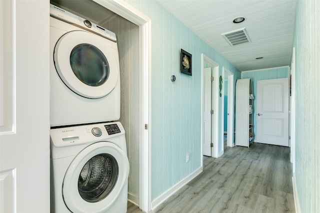 clothes washing area with light wood-type flooring and stacked washer / drying machine