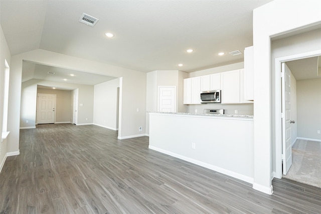 kitchen featuring white cabinetry, dark wood-type flooring, stainless steel appliances, and light stone counters