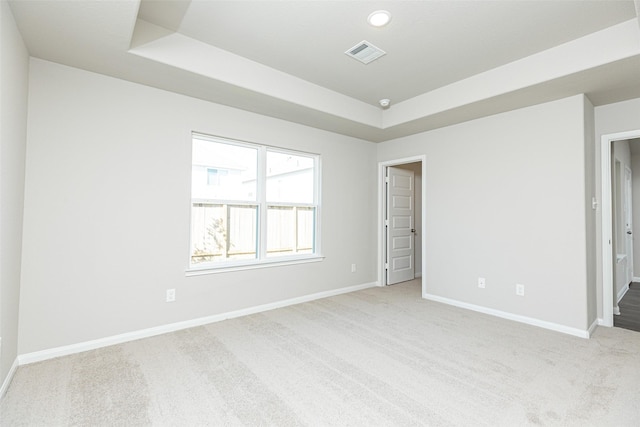 unfurnished room featuring a raised ceiling and light colored carpet