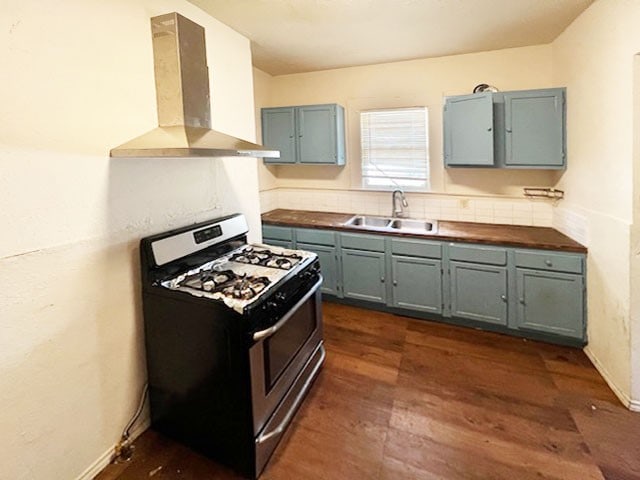 kitchen with butcher block countertops, wall chimney range hood, dark hardwood / wood-style flooring, range with gas stovetop, and sink