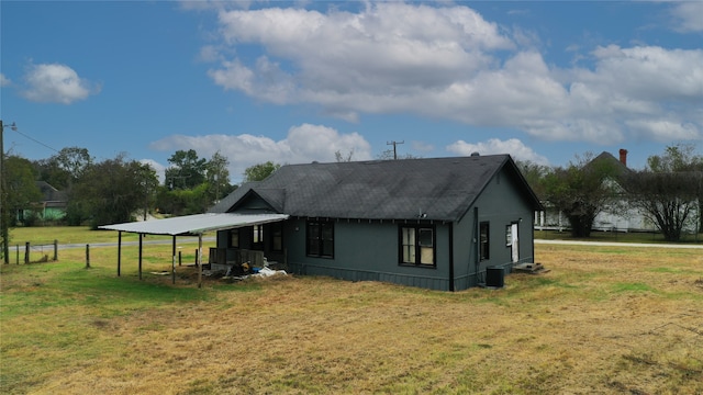 rear view of house featuring central AC unit and a yard