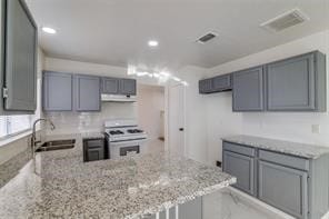 kitchen with light stone counters, sink, white electric stove, and gray cabinetry