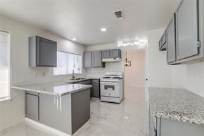 kitchen featuring kitchen peninsula, gray cabinets, white range oven, and sink