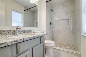 bathroom featuring vanity, toilet, and a tile shower