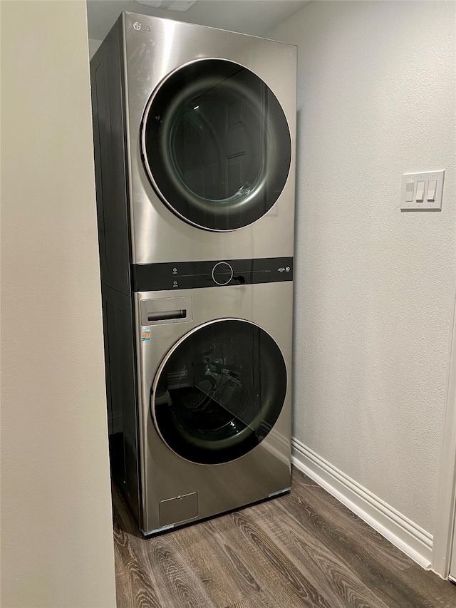 laundry room featuring stacked washer and clothes dryer and dark hardwood / wood-style flooring