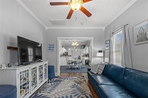 living room with hardwood / wood-style flooring, ceiling fan with notable chandelier, and crown molding