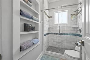 bathroom featuring toilet and a tile shower