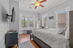 bedroom with dark wood-type flooring, ornamental molding, and ceiling fan