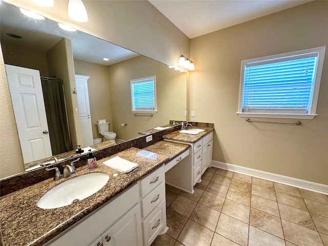 bathroom with tile patterned floors, vanity, toilet, and a wealth of natural light